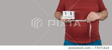 fat man measures the size of the abdomen with a centimeter measuring tape. September 15, Losing Weight Day. fat man measures the size of the abdomen with a centimeter measuring tape. September 15, Losing Weight Day. 77071828