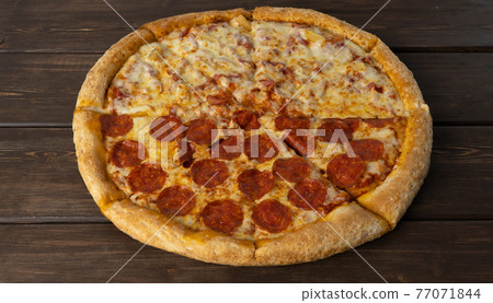 delicious pizza on a wooden background. Peperoni and Hawaiian, combined pizza in two parts. traditional Italian dish delicious pizza on a wooden background. Peperoni and Hawaiian, combined pizza in two parts. traditional Italian dish 77071844