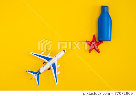 Airplane tube of sun cream and a red starfish on a yellow background. Summer vacation concept. 77071909