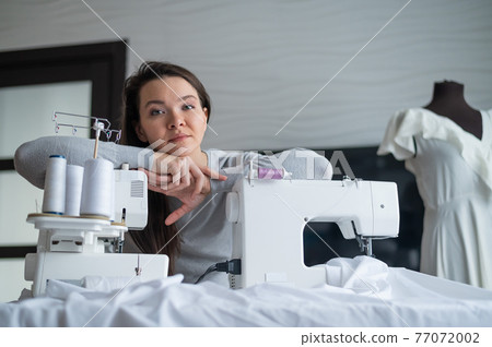 Young caucasian woman sews at home 77072002