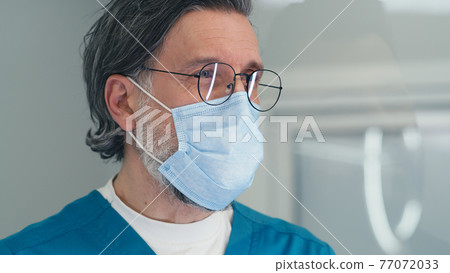 Mature doctor in mask speaking with patient on reception in medical center Mature doctor in mask speaking with patient on reception in medical center 77072033