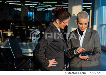 Two young business women looking at digital tablet in office. 77072210