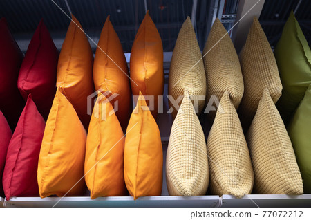 A row of colorful pillows on a shelf in a textile store. A row of colorful pillows on a shelf in a textile store. 77072212