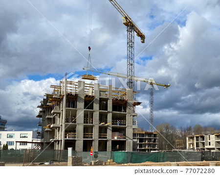 Construction of new high-rise building in the city two construction cranes in a construction site Construction of new high-rise building in the city two construction cranes in a construction site 77072280