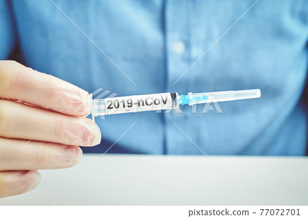Doctor holds a syringe with the inscription 2019-nCoV virus. Virus epidemic concept. Doctor holds a syringe with the inscription 2019-nCoV virus. Virus epidemic concept. 77072701