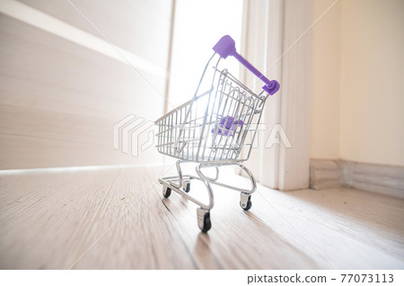Grocery cart at the open door. Delivery of products. Mini trolley for contactless delivery. Grocery cart at the open door. Delivery of products. Mini trolley for contactless delivery. 77073113
