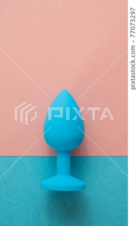 Blue anal plug on a pink background. Plastic sex toy for alternative sex. Copy space. 77073297