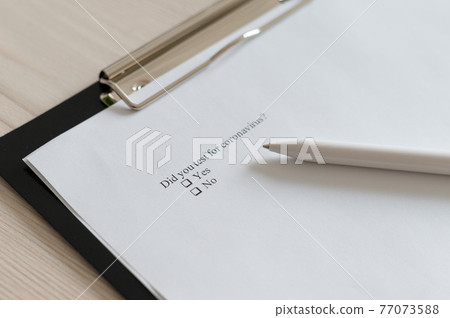 Coronavirus test questionnaire and pen on the table. Checklist for questions about covid-19. 77073588