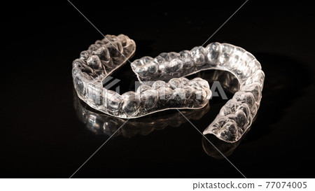 Removable plastic retainers for bite correction on a black background 77074005