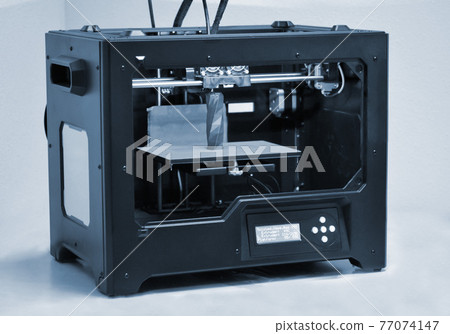 3D printer works and creates an object from the hot molten plastic 77074147