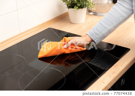 Woman cleaning induction stove Woman cleaning induction stove 77074438