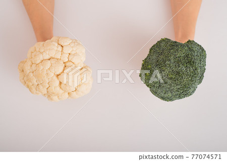 Broccoli and cauliflower in female hands on a white background. Empty space. 77074571