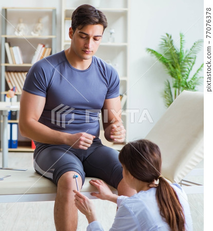 Doctor checking patients joint flexibility with gonimeter Doctor checking patients joint flexibility with gonimeter 77076378