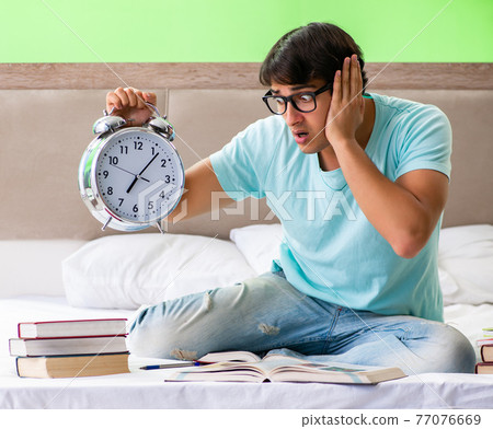 Student preparing for exams at home in bedroom sitting on the be 77076669