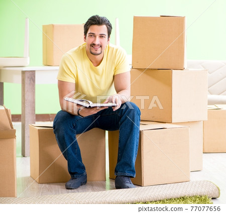 Young handsome man moving in to new house with boxes 77077656