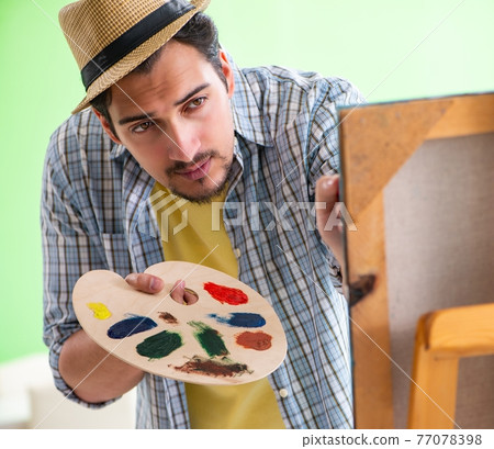 Young male artist working on new painting in his studio Young male artist working on new painting in his studio 77078398