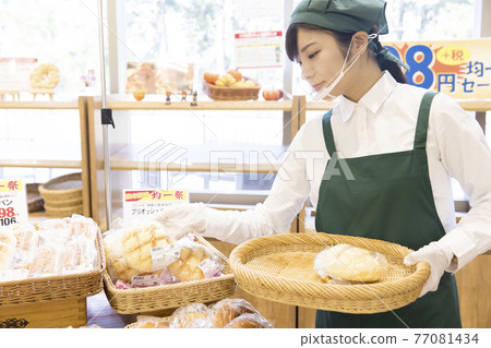 Employee woman lining up bread at a bakery Employee woman lining up bread at a bakery 77081434