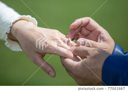 一個男人的手在女性上戴著一根手指 77081667