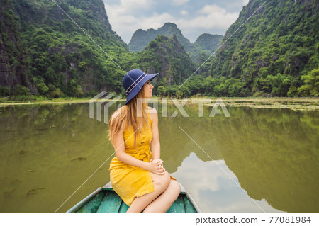 Woman tourist in boat on the lake Tam Coc, Ninh Binh, Viet nam. It's is UNESCO World Heritage Site, renowned for its boat cave tours. It's Halong Bay on land of Vietnam. Vietnam reopens borders after 77081984