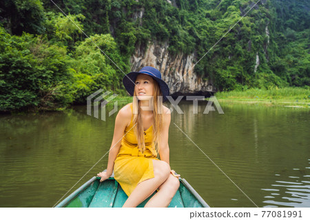 Woman tourist in boat on the lake Tam Coc, Ninh Binh, Viet nam. It's is UNESCO World Heritage Site, renowned for its boat cave tours. It's Halong Bay on land of Vietnam. Vietnam reopens borders after 77081991