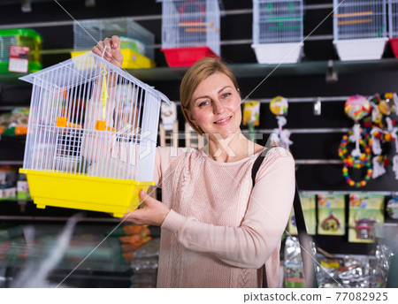 Portrait of smiling female customer buying cage for bird 77082925
