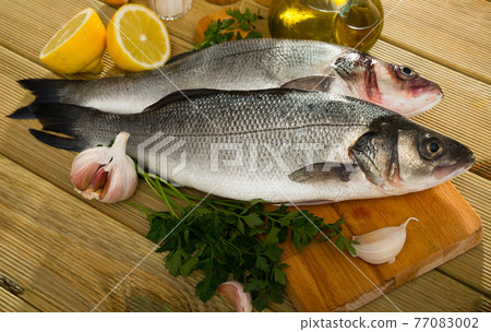 Sea basses on cutting board Sea basses on cutting board 77083002
