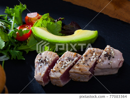 Tasty raw tuna fish , fresh avocado and greens served at plate Tasty raw tuna fish , fresh avocado and greens served at plate 77083364