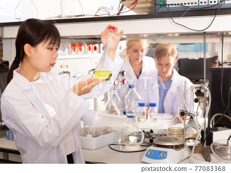 Chinese female scientist holding flask 77083368