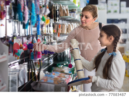 Woman with daughter visiting pet shop to buy scratching post Woman with daughter visiting pet shop to buy scratching post 77083487