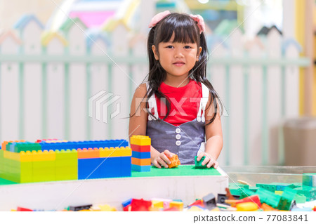 Children play with colorful plastic toys blocks on table 77083841