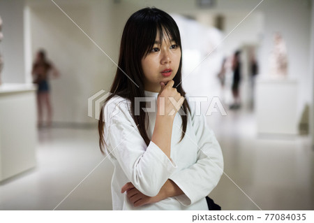 Thoughtful chinese young woman near picture collection 77084035