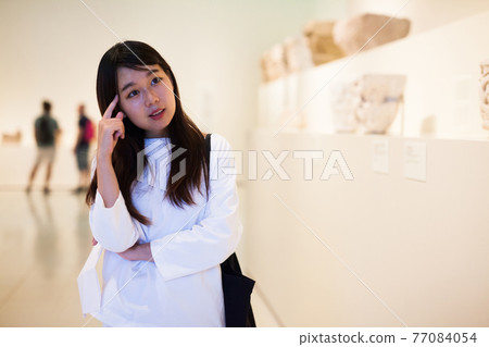 Thoughtful chinese woman in historical museum looking at art object Thoughtful chinese woman in historical museum looking at art object 77084054