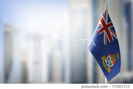 A small flag of Cayman Islands on the background of a blurred background 77085725