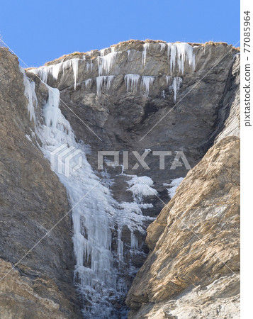 frozen waterfall and ice stalactites on a rock face frozen waterfall and ice stalactites on a rock face 77085964