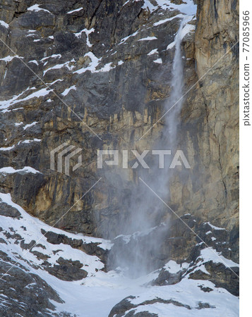 Snow , ice and stones falling from a vertical mountain wall Snow , ice and stones falling from a vertical mountain wall 77085966