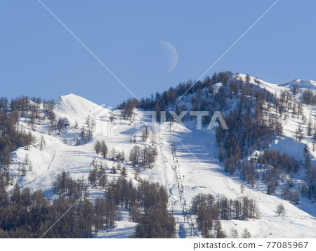 mountain landscape with ski slopes, ski lifts and half moon 77085967