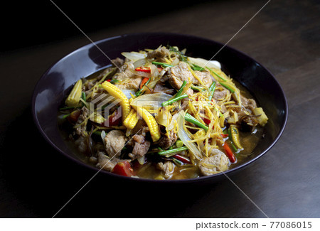 Stir fried pork and ginger with mixed vegetable in a black plate on wooden table 77086015