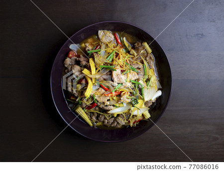 Stir fried pork and ginger with mixed vegetable in a black plate on wooden table 77086016