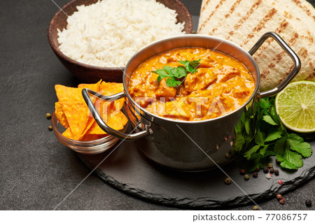 Pot of Traditional Chicken Curry, bowl of rice and pita on stone serving board Pot of Traditional Chicken Curry, bowl of rice and pita on stone serving board 77086757