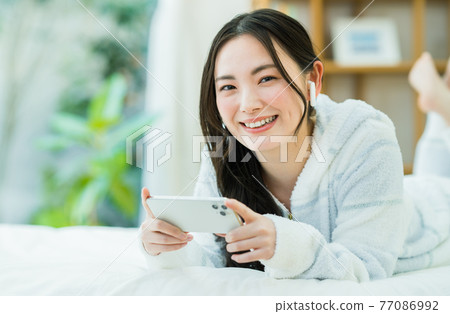 一個年輕的女人,看著她的智能手機上的視頻 一個年輕的女人,看著她的智能手機上的視頻 77086992