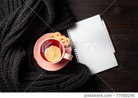 Clear copybook with cup of tea on black wooden background 77088286