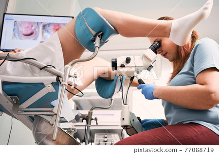 Gynecologist examining female patient with colposcope. 77088719