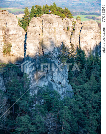 Czech flag at the top of the rock and climer in the wall. Sandstone rocks Czech flag at the top of the rock and climer in the wall. Sandstone rocks 77088843