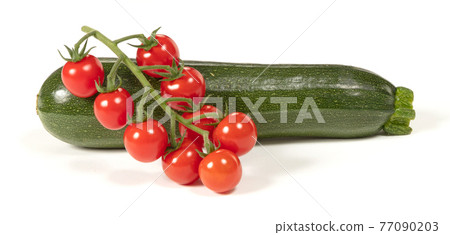 Twig of fresh cherry tomato and a zucchini, isolated Twig of fresh cherry tomato and a zucchini, isolated 77090203