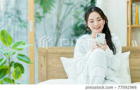 看一台智能手機的少婦在臥室 77092966