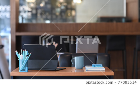 Front view of contemporary workplace with a tablet computer, coffee cup, notebook and stationery on wooden desk. 77093514