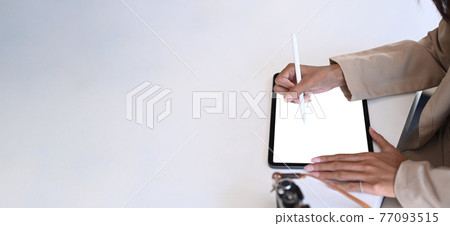 Over head shot of photographer or designer working with digital tablet on white desk and copy space. Over head shot of photographer or designer working with digital tablet on white desk and copy space. 77093515