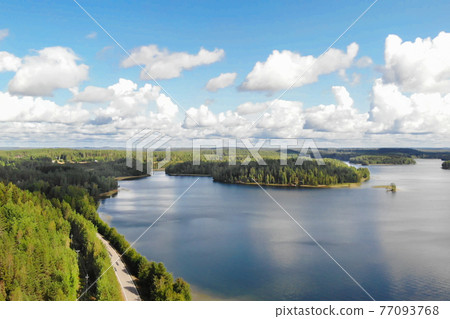Aerial view of lake with island, road and forest on a summer sunny day in Finland. Drone photography Aerial view of lake with island, road and forest on a summer sunny day in Finland. Drone photography 77093768