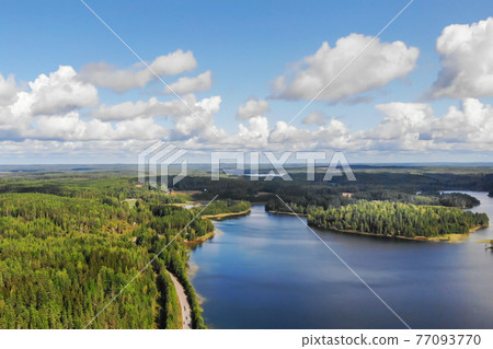 Aerial view of lake with island, road and forest on a summer sunny day in Finland. Drone photography Aerial view of lake with island, road and forest on a summer sunny day in Finland. Drone photography 77093770