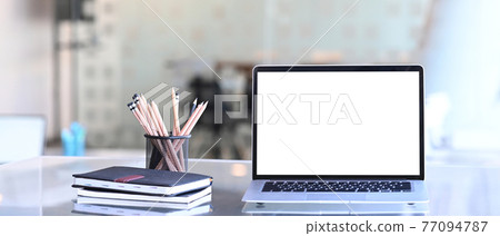 Front view of laptop computer stationery and notebook on creative workspace. Blank screen for graphics display montage. Front view of laptop computer stationery and notebook on creative workspace. Blank screen for graphics display montage. 77094787